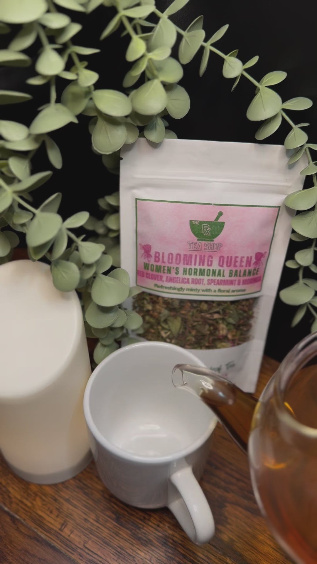 Short video clip of blooming queen tea being poured into white mug from clear teapot with green scenery 